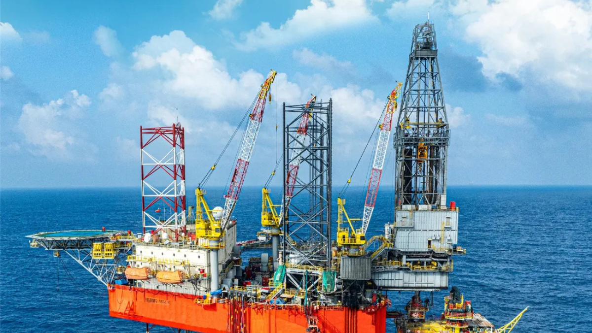 Offshore drilling platform with cranes operating at sea under cloudy sky