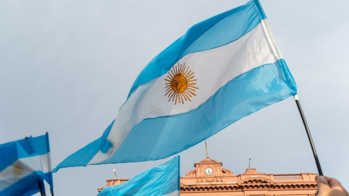 Argentine flag waving in front of a historic government building