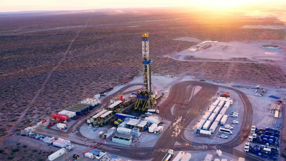 Aerial view of Vaca Muerta drilling site with rigs, equipment, and desert landscape at sunrise