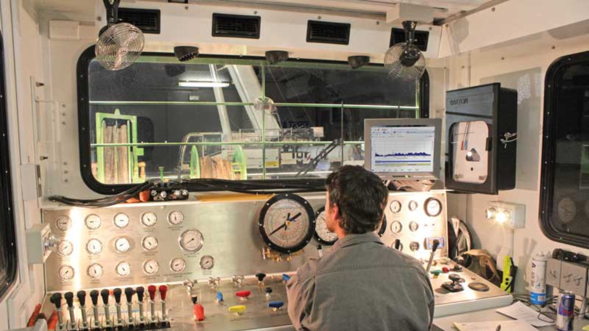 Operator monitoring drilling controls and gauges inside a Vaca Muerta control cabin