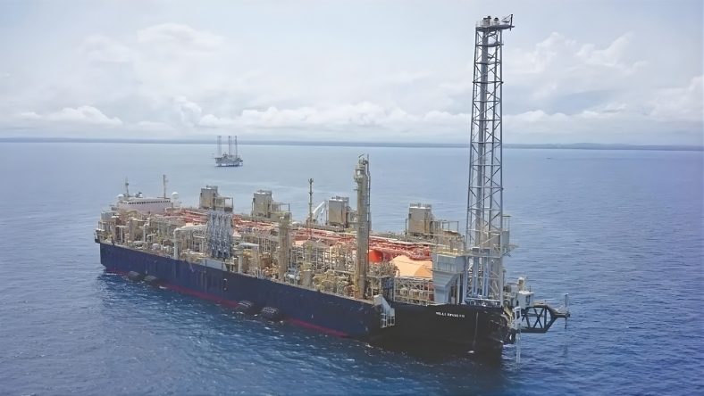 Floating LNG production vessel operating offshore with processing towers and deck equipment