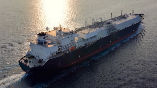 Aerial view of a large LNG carrier underway at sea during golden hour with calm open water surrounding